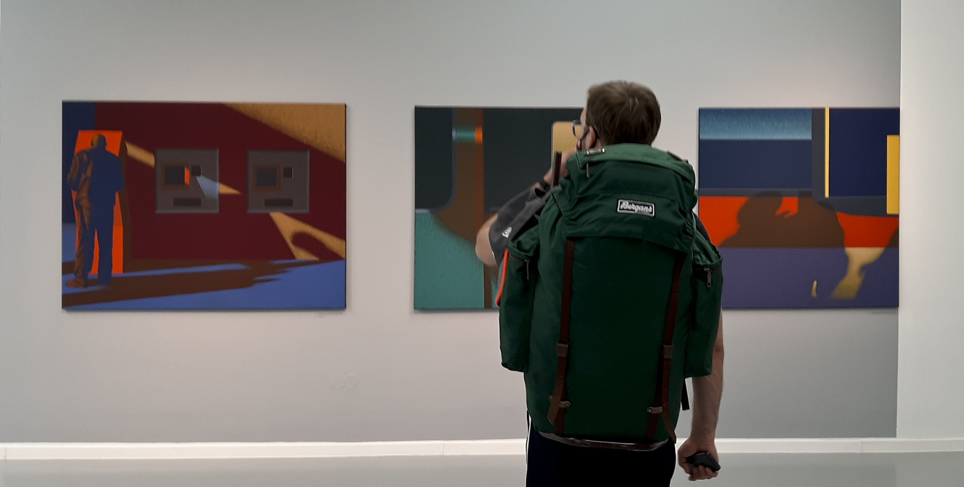 Mężczyzna ogląda obrazy Dariusza Milczarka na wystawie pokonkursowej w Galerii Miejskiej BWA w Bydgoszczy